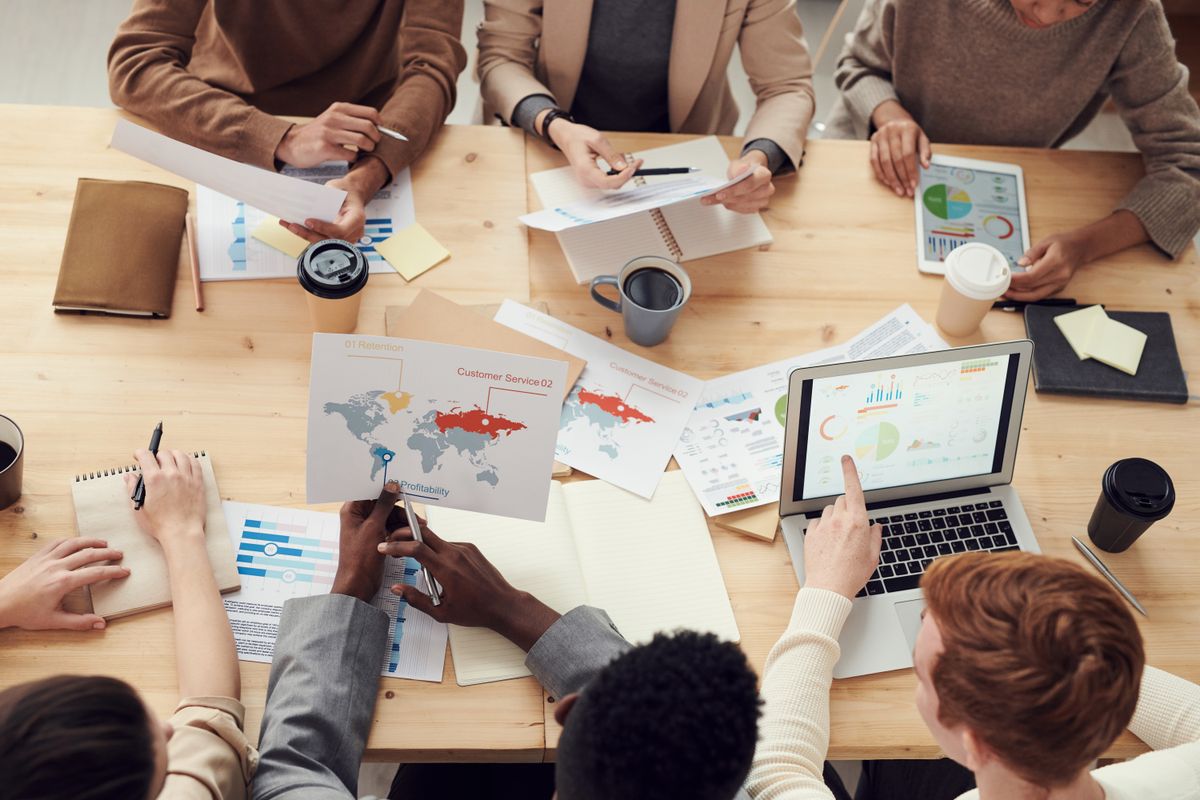 Team plant Marketing mit Weltkarte und Auswertungen am Tisch